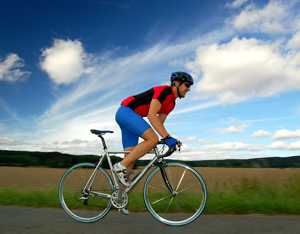 Picture of a man riding a bicycle next to a field.