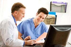 Picture of two doctors smiling and looking at a computer.