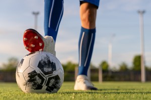 Athlete standing with ball on football field during sunrise. soccer ball in net on sky background. ball movement. popular sports on football club.