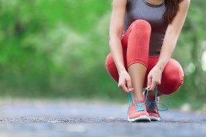 Picture of a female runner bending down to tie her shoe.