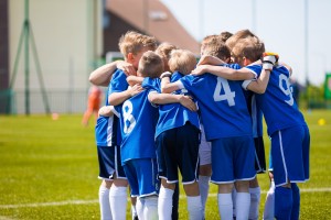Picture of young boys on a soccer team huddling on the field.